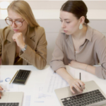 two women with laptops